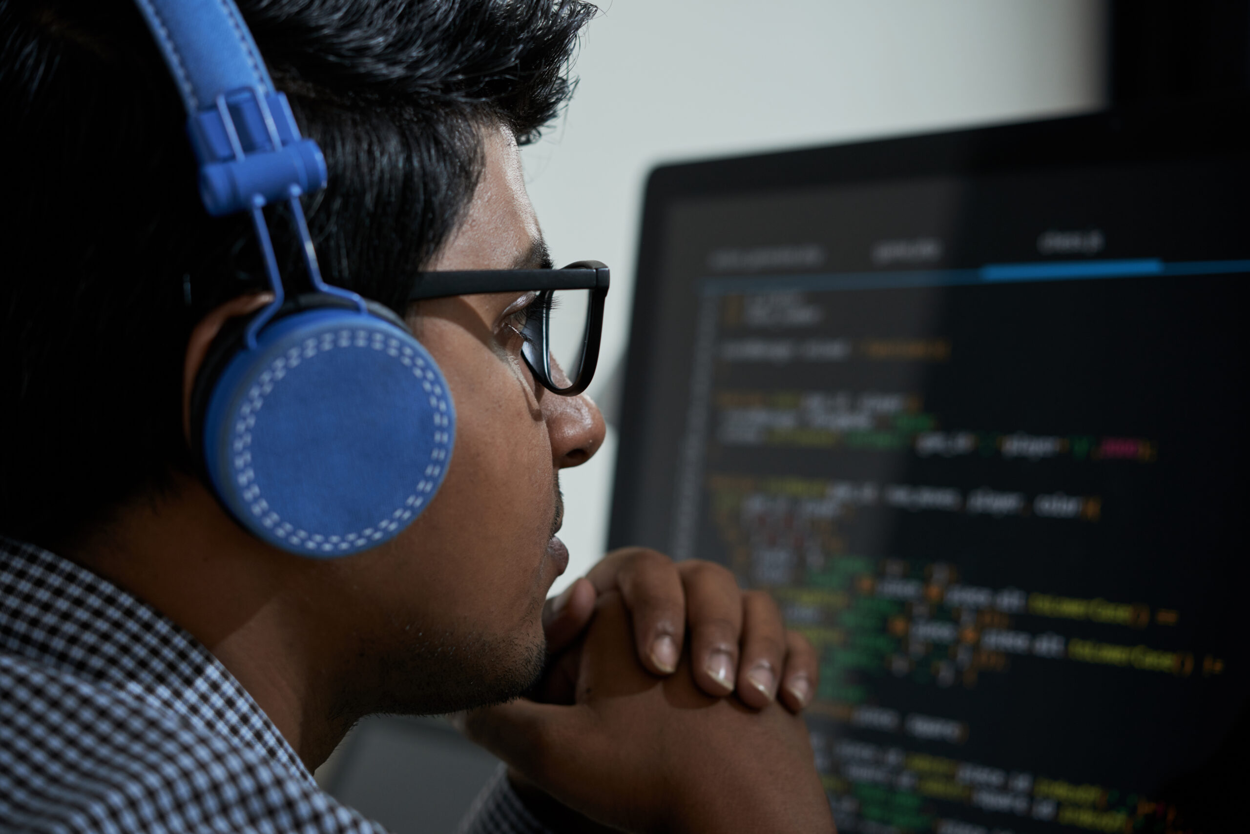 Pensive Indian software developer looking at programming code